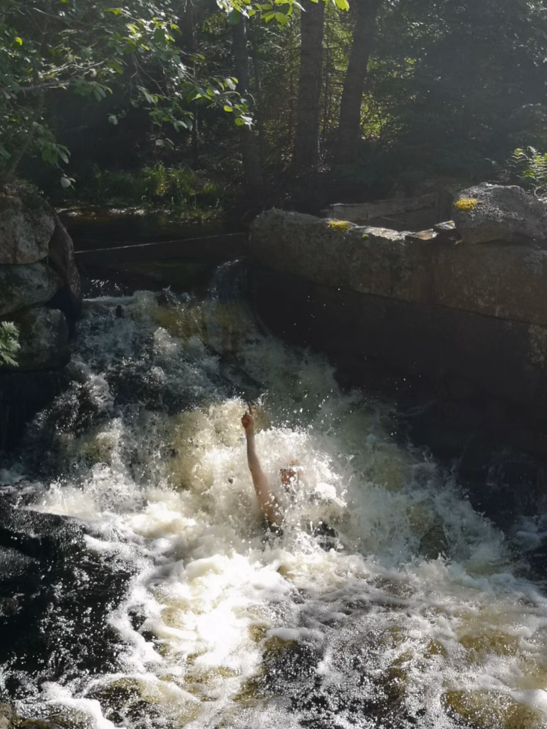 Seikkailu-uimari nauttii vesiputouksen voimasta